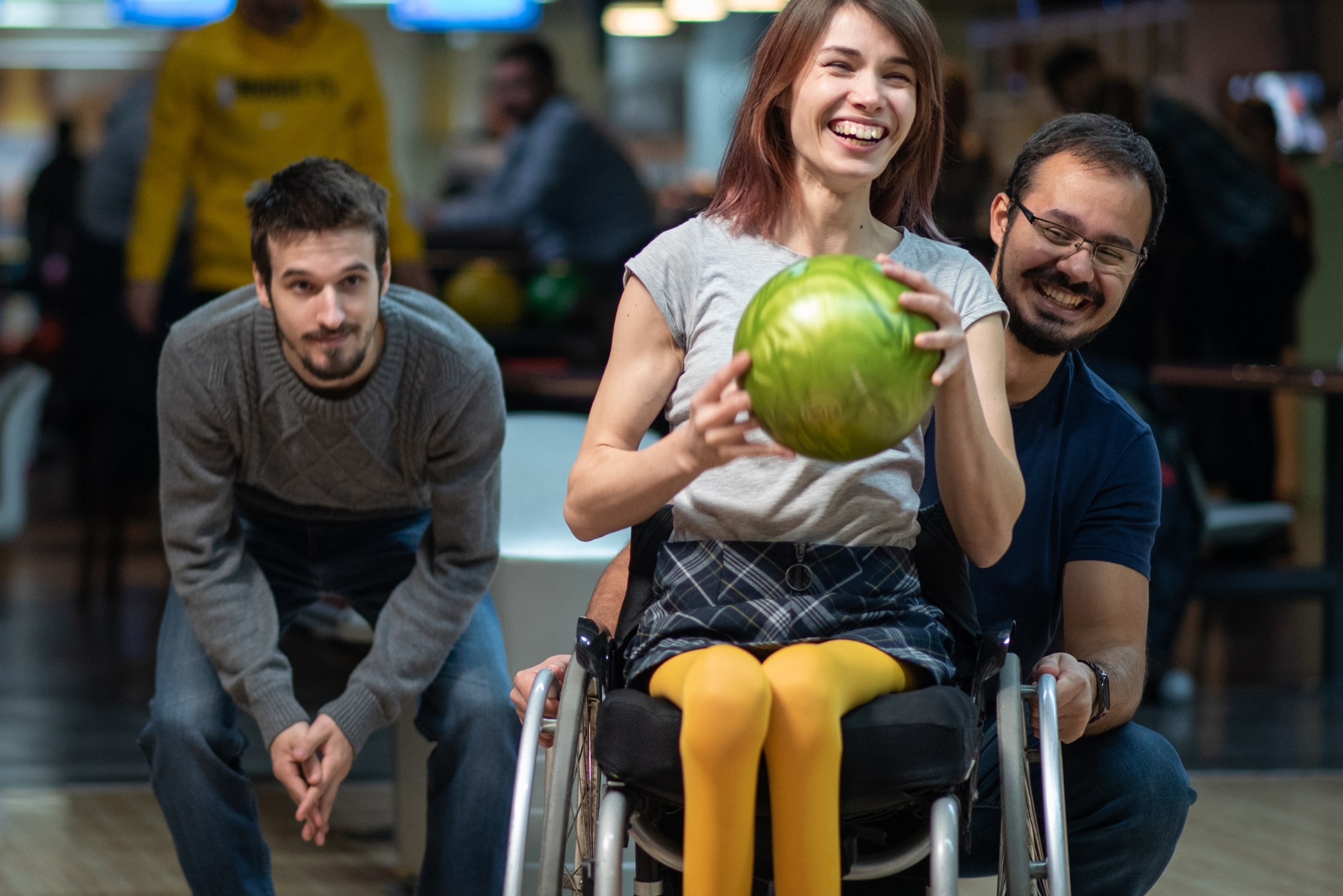 A female sitting in a wheelchair holding a bowling ball