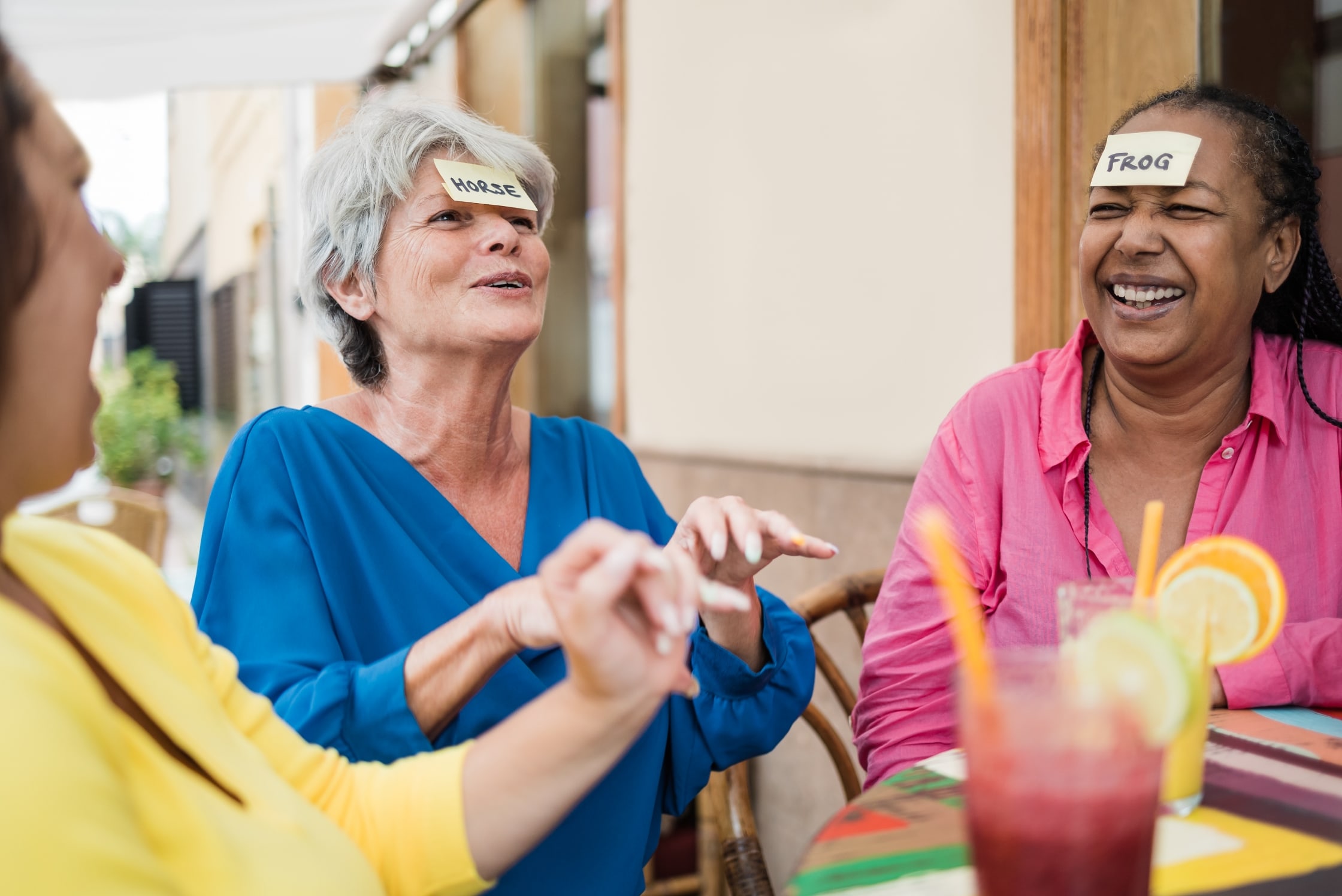 Two women playing a game with words stuck on to their foreheads