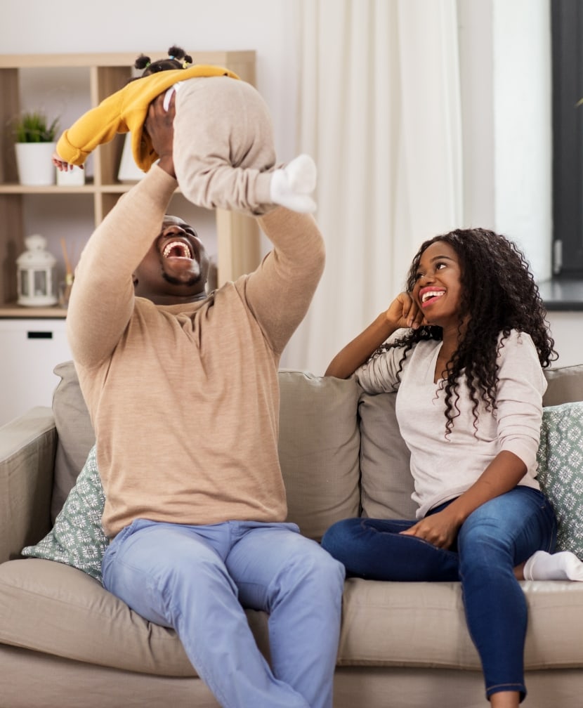 Mother, father and daughter playing on the sofa